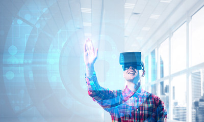 Young man in modern office interior experiencing virtual reality technology