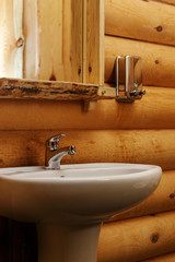 A mixture of traditional Russian wooden construction with logs, round bars on the wall of the house with modern ceramic wash sink