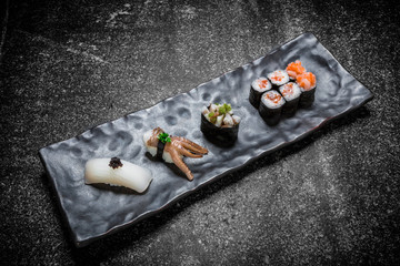  Japanese seafood sushi , roll and chopstick on a black plate