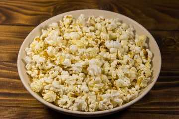 Bowl with popcorn on wooden table