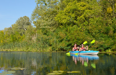 Family kayaking, mother and daughter paddling in kayak on river canoe tour having fun, active autumn weekend and vacation with children, fitness concept
