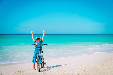 Obraz na płótnie Canvas little boy riding bike on tropical beach