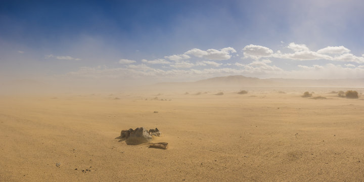 Stone ring forms a fire pit in a vast sand desert under the cloud of a growing sandstorm.