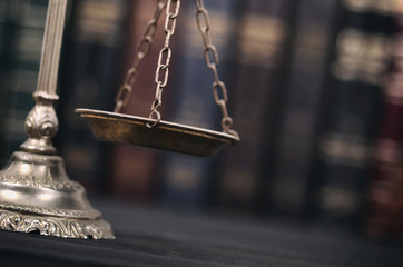  Scales of Justice on a black wooden background.