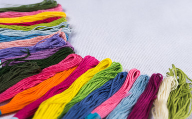 Colored thread for embroidery on white canvas. Copy spase.