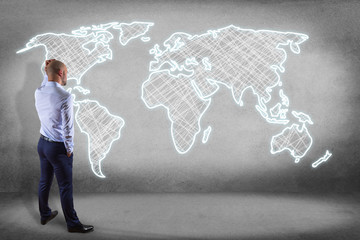 Businessman in front of a wall with a Hand drawn world map on a futuristic interface