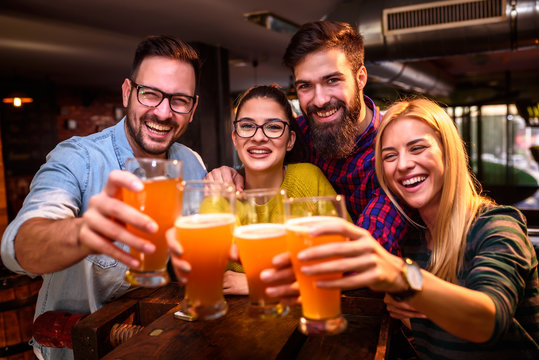 Group Of Young Friends In Bar Drinking Beer Toasting