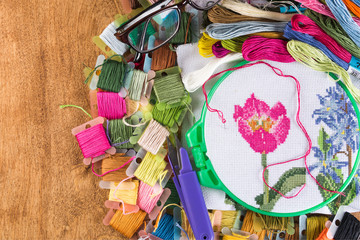The process of cross-stitch. Canvas on hoops, needles, embroidery floss and pattern.