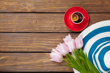 Cup of english tea with spring tulips and hat