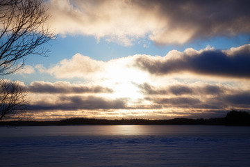 View of the winter lake under the snow and sunset