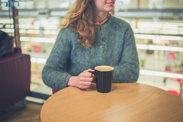 Young woman drinking coffee in airport