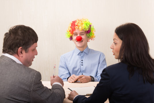 Funny portrait of young man during job interview and members of managemen