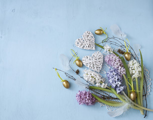 on a blue background the Easter composition: eggs, hyacinths, feathers, hearts and birch branches