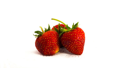 Three Red strawberries on tissue paper on white background