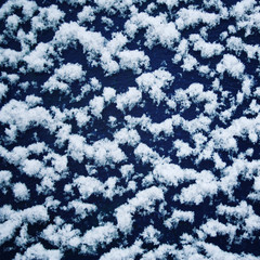 Blue wooden surface covered with snow. Fluffy snowflakes on the roof. Natural background. Cold winter day. Close up. Winter in Russia. Toned photo.