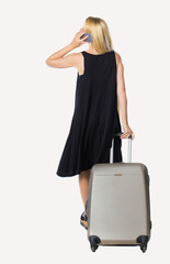 Back view of woman with suitcase talking on the phone.