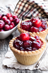 egg  custard tarts with cranberry jam and wild apples on wooden table