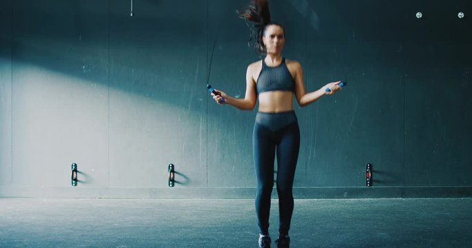 Beautiful athletic woman exercising jumping rope in the gym