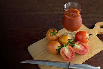 Fresh Tomatoes and tomato juice on chopping wood all put on the wooden table