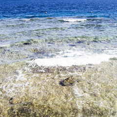 Shallow waters and blue sea. Waves and rocks in the water