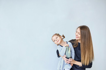 portrait of happy mother with daughter having good time. little cute girl playing with cactus on gray background.