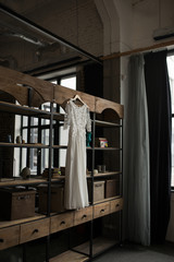Rustic white wedding dress hanging on the cupboard. Loft interior