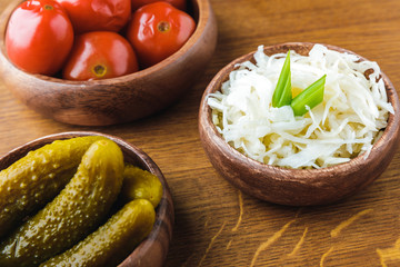close-up view of delicious pickled vegetables in bowls on wooden tabletop