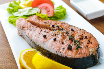 close-up view of gourmet roasted salmon with lemon slices and vegetable salad