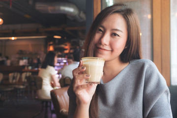 Closeup image of a beautiful asian woman holding and drinking coffee with feeling relaxed in cafe