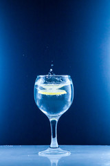 Glass glass of water with lemon on the isolated background. Mountain mineral pure mountain water with gas bubbles and a lemon slice and spray tonic refreshing sports drink.