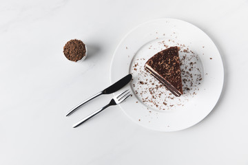 Bowl with grated chocolate and cake on plate