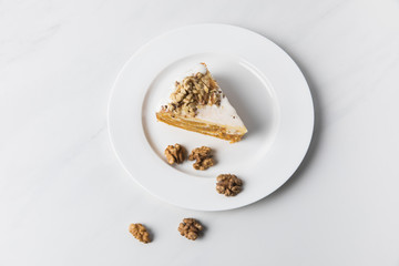 Cake and walnuts on plate placed white surface