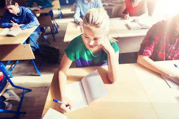 group of students with books writing school test