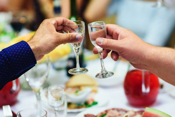 hands with glasses of vodka at a festive event