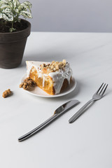Cake on plate, walnuts and cutlery with potted plant on table