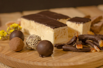 Bird's milk souffle cake with many chocolate candies on wooden table 