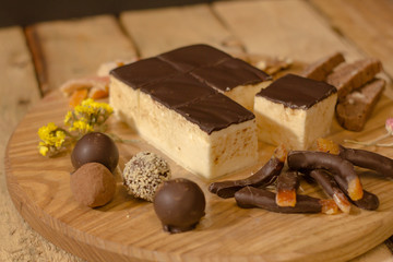Bird's milk souffle cake with many chocolate candies on wooden table 