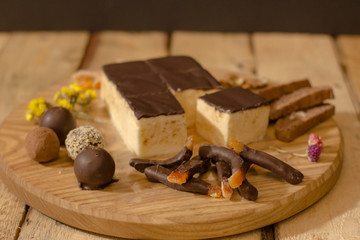 Bird's milk souffle cake with many chocolate candies on wooden table 