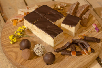 Bird's milk souffle cake with many chocolate candies on wooden table 