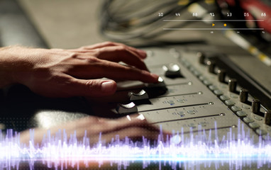 hands on mixing console in music recording studio