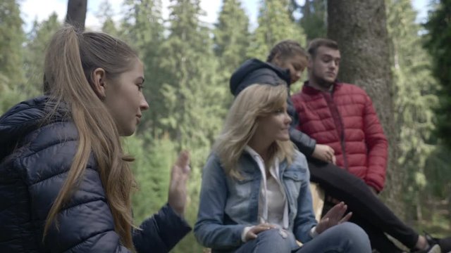 Teenage group of friends spending time in nature singing and cheering in the forest
