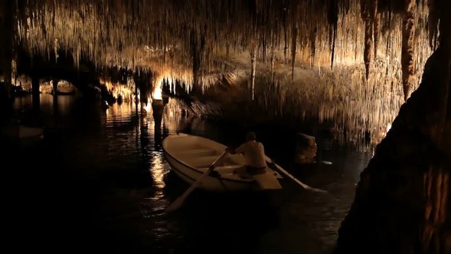 MAJORCA, SPAIN Tourists float on a boat on the underground lake in the famous stalactite caves of Dragon (Cuevas del Drach)