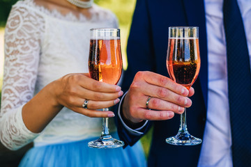 bride and groom hands with champagne glasses with rings close-up