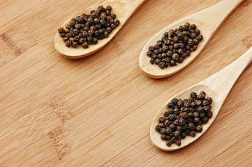 black pepper in wooden spoons on a cutting board