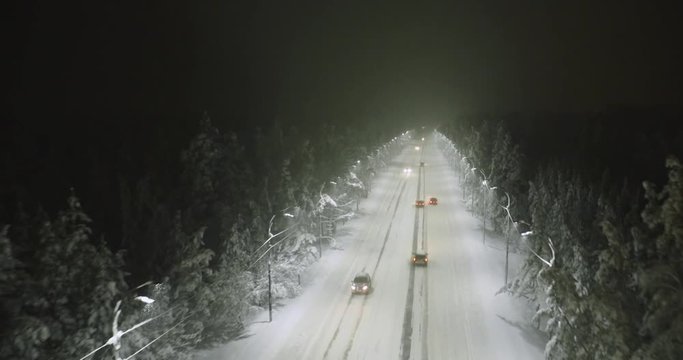 aerial shot cars drive on winter night road during snowfall