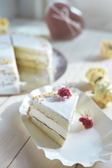 light diet layered biscuit with curd cream and cherry. cake covered with curd cream and garnished with dried roses on the white wooden background