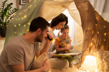 happy family reading book in kids tent at home