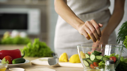Obraz na płótnie Canvas Young cooking girl squeezing fresh lemon juice in salad bowl, vegan, vegetables