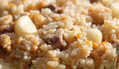 Pilaf from rice and meat with the addition of carrots and garlic. Prepared meal before consumption, fatty product close-up.