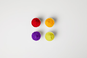 Obraz na płótnie Canvas top view of four colors of holi powder in bowls on white, Hindu spring festival